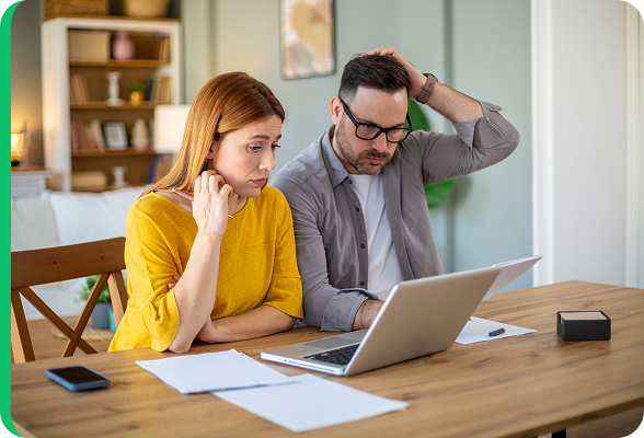 Couple préoccupé regardant un ordinateur portable à la maison, analysant leur facture d’énergie ou le tarif capacitaire.