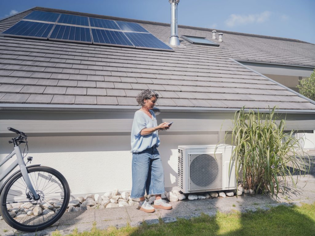 Mevrouw telefoneert naar expert terwijl ze bij haar luchtwaterwarmtepomp staat (1)